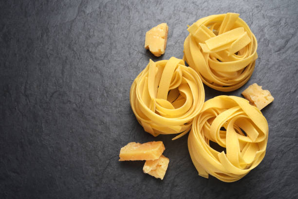 fettuccine con parmigiano su sfondo nero - italian cuisine dry pasta directly above foto e immagini stock