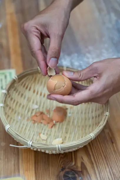 Photo of Beppu spring egg, people hold boiled yellow egg with two hands and peel off, Beppu spring egg from Kamado Jigoku Cooking Pot Hell Beppu Onsen, Oita, Japan.