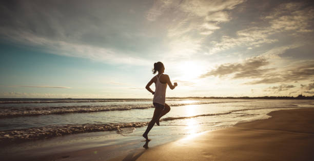 istock Fitness woman runner running on sunset beach 1179919378