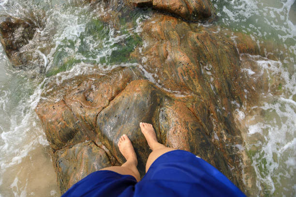 istock Legs stand on rock  covered with sea grass and waves 1179921650