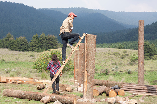 Mexico city, Mexico, September 01, 2018: man on top of a wooden ladder and a woman in the countryside surrounded by mountains. Travel concept