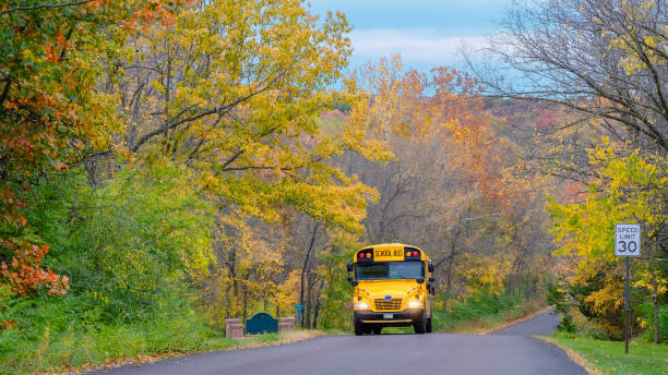 istock School bus driving along suburban street in fall 1179925252