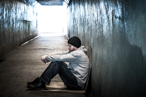 Joven sin hogar sentado en el túnel del metro frío photo