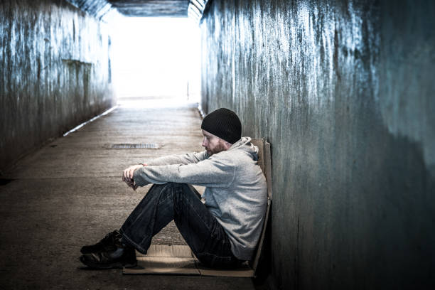 homeless young man sitting in cold subway tunnel - vagabundo imagens e fotografias de stock