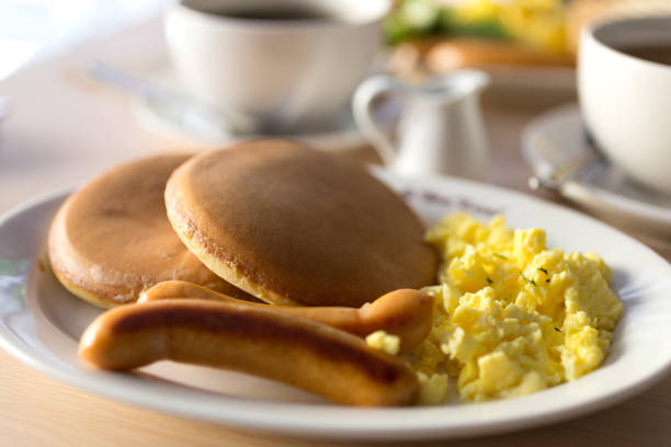 istock Close up breakfast with sausages, bread, scrambled eggs and pancakes on white plate, macro 1179934285