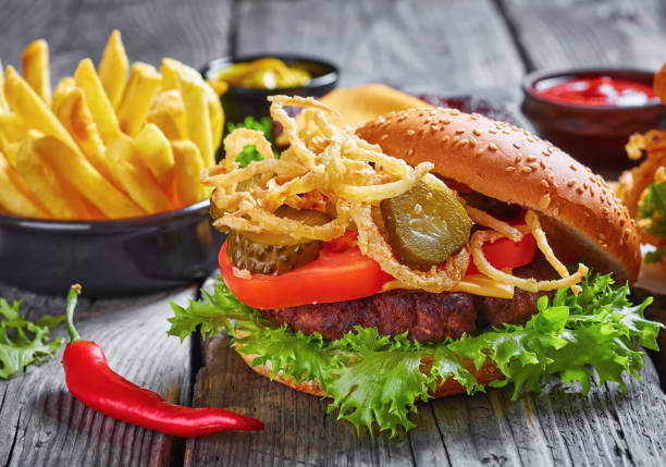 istock Cheeseburger with cheddar cheese, crispy fried onions, lettuce, sliced tomatoes, pickles, french fries 1179934638