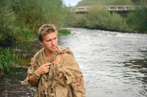 istock young medieval peasant in an old burlap suit walks across the river 1179935427