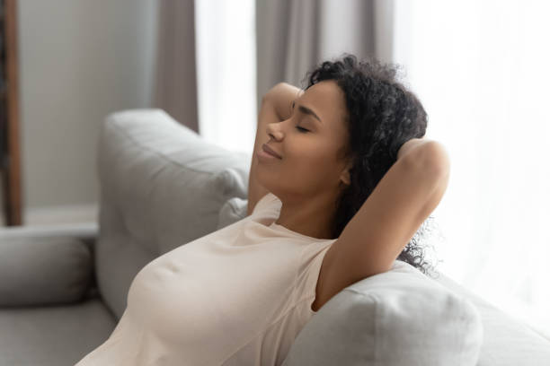 istock Calm black young woman relax on sofa hands over head 1179938837