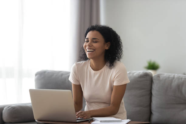 istock Happy black woman laughing using laptop typing 1179938854