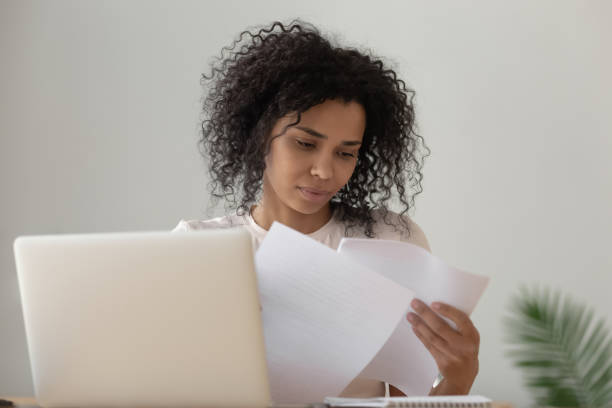 istock Focused black girl read paperwork studying on laptop 1179938895