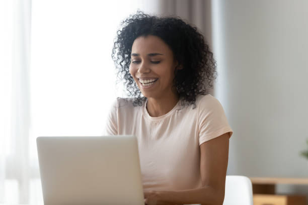 istock Smiling biracial woman laughing using laptop messaging 1179938907