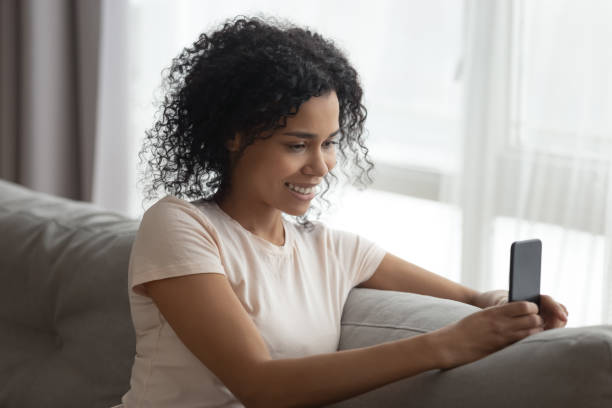 istock Smiling black young woman using cellphone making selfie 1179938915