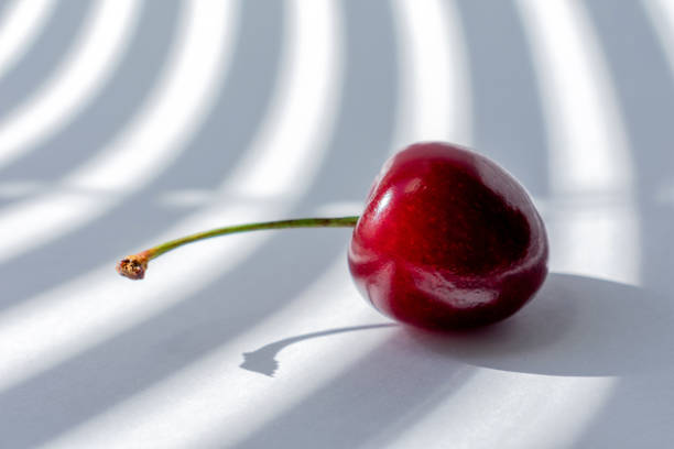 istock cherry on white background illuminated by the rays of the sun 1179940712