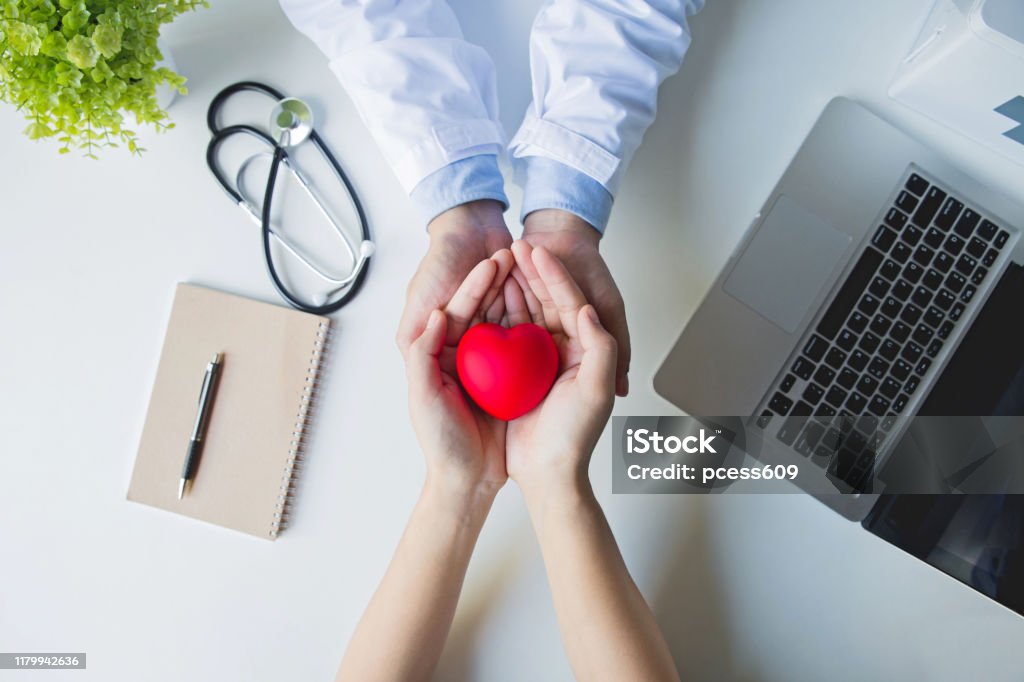 Top view .doctor and patient hands holding red heart on white table, health care love, give, hope and family concept, world heart day,world health day World Health Day Stock Photo