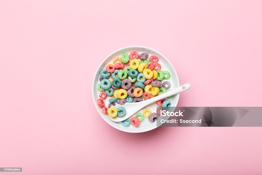 Anéis de milho coloridos na bacia com leite e colher no fundo cor-de-rosa - Foto de stock de Tigela - Louça royalty-free