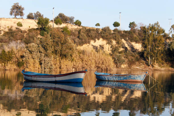 Reflection of Kolae boat, traditional Thai-Malayu fishing boat on the river at sunset. Traditional Thai-Malayu house and Islamic mosque background. Blue tone. The Bang Nara River, Narathiwat, Thailand.