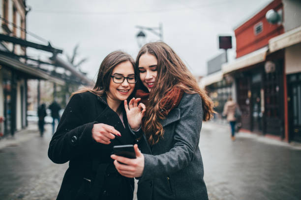 Two female friends using phone downtown