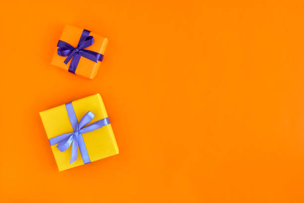 istock Two gift boxes with ribbon and bow on orange background . Top view and space for text. 1179951473