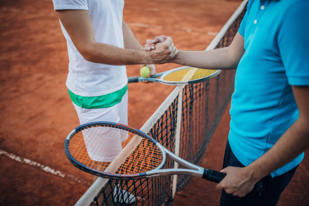 Two tennis players handshake after game Two men, tennis players fair play after a match on tennis court, handshake after a match. clay court stock pictures, royalty-free photos & images