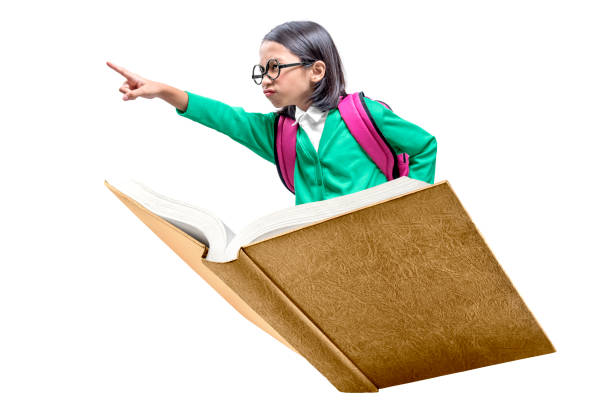 istock Asian cute girl with glasses and backpack sitting on book pointing forward 1179954303
