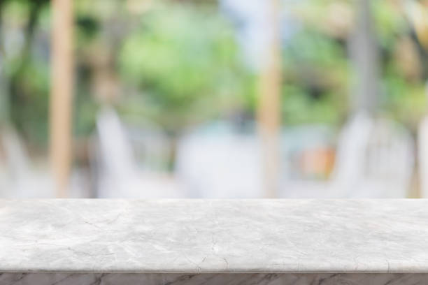 istock Empty white stone marble table top and blurred of interior restautant with window view green from tree garden background background - can used for display or montage your products. 1179954697