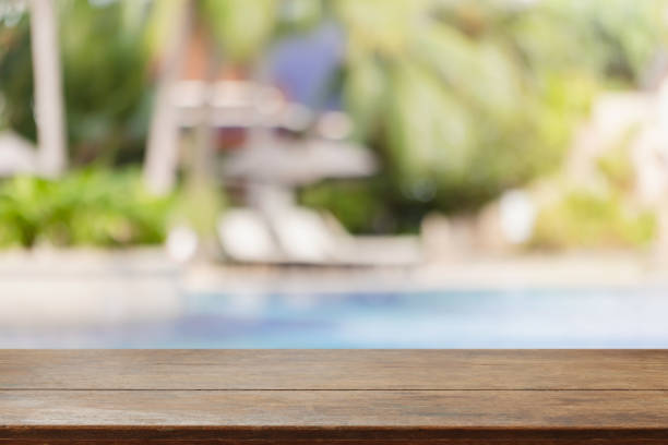 istock Empty wood table top and blurred swimming pool in tropical resort in summer background - can used for display or montage your products. 1179954708