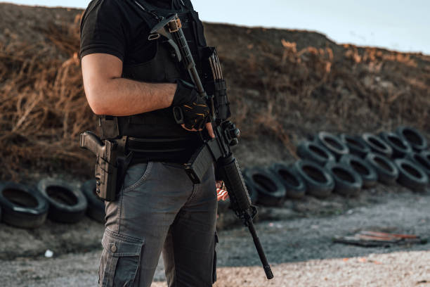 Image of armed man with rifle and gun standing outdoors, close-up.