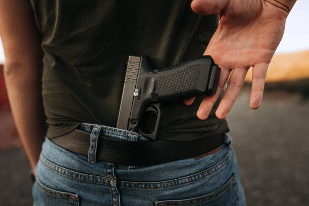 istock Hand of a man reaching for a gun hidden behind his back. 1179956422