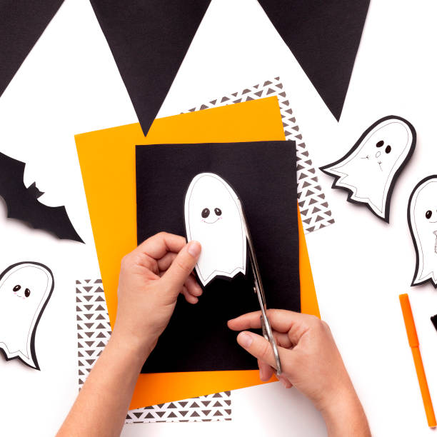 istock Process of woman cutting out small paper Halloween ghost 1179956476