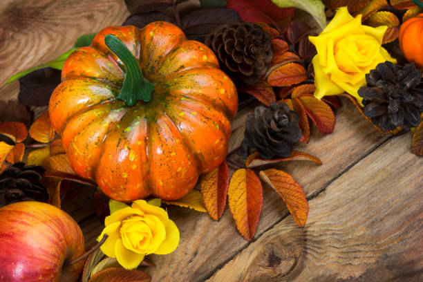 istock Fall pumpkin, cones, yellow roses arrangement 1179957180