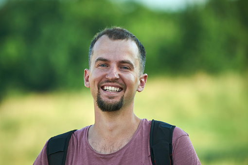 portrait of a smiling young man in a park.