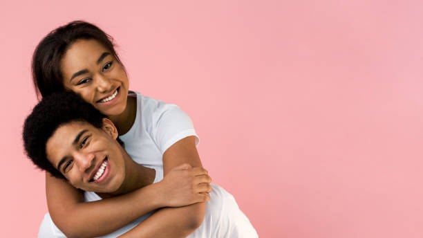 istock Happy guy carrying his girlfriend on back, pink background 1179959358