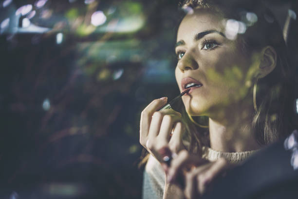 istock Young beautiful woman applying make-up in the car. 1179960236