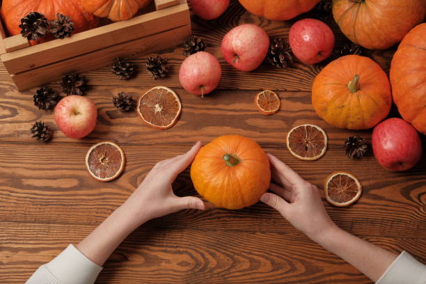 istock Female hands hold an orange pumpkin. top view 1179962831