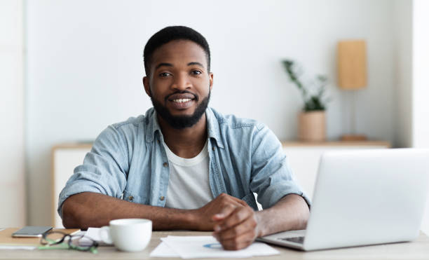 istock Smiling african american worker looking at camera, sitting at workplace 1179963946