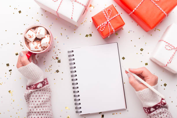 Woman with notepad, cacao and Christmas presents