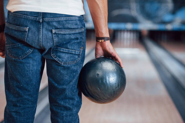 vista de partículas traseras del hombre con ropa casual jugando a los bolos en el club - bowling holding bowling ball hobbies fotografías e imágenes de stock