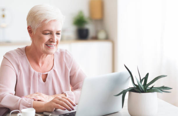 istock Smiling senior business lady looking at laptop 1179965483