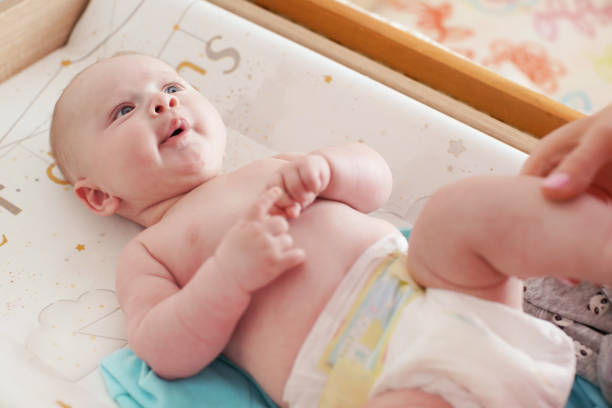 istock 4 months old infant boy lying on changing desk, mother hands holding his legs 1179967949