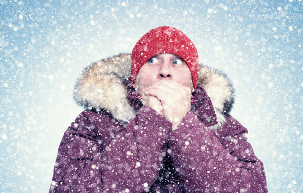 istock Frozen man in red winter clothes warms his hands, cold, snow, frost, blizzard 1179968409