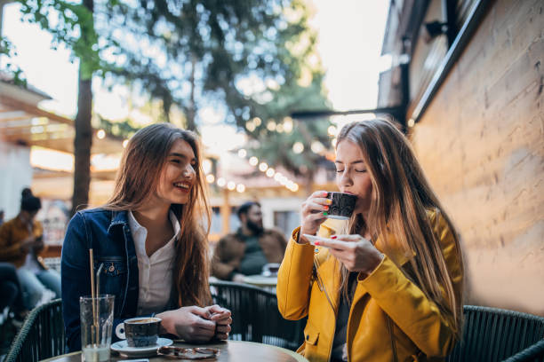 istock Young women sitting in sidewalk cafe 1179968766