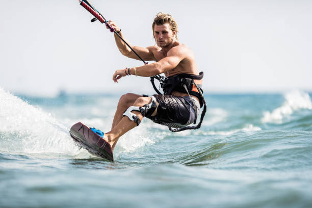 Muscular build man surfing on kiteboard during summer day at sea. Copy space.