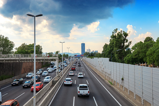 Vienna, Austria - 19 June 2019: Highway with riding cars and skyscrapers on horizon, top view