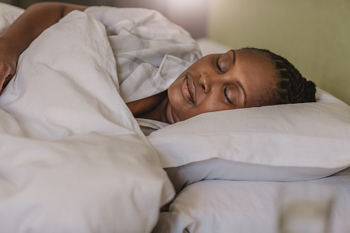 Mature African American woman sound asleep under a duvet in her bed at home in the early morning