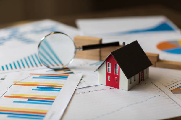 Miniature house with a magnifying glass on the background