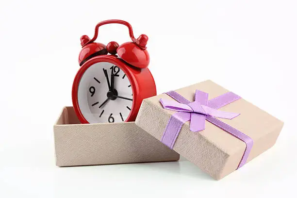 Photo of Red alarm clock in a cream box with lilac ribbon