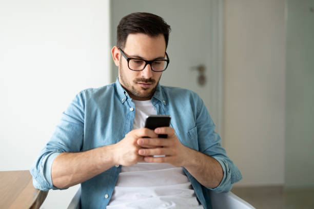 istock Young smiling man surfing the net and text messaging with mobile phone 1179976601