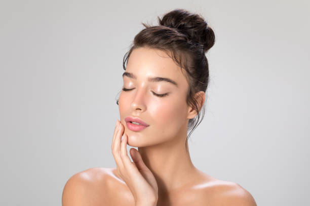 Woman beauty portrait Close up studio shot of a beautiful woman with perfect skin, she touching her face hair bun stock pictures, royalty-free photos & images