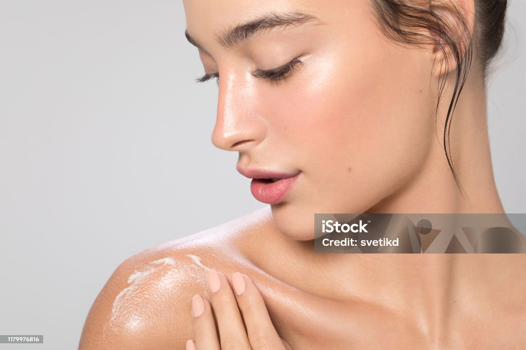 Woman body care Close up studio shot of a beautiful woman with perfect skin, she applying cream at her shoulder Skin Care Stock Photo