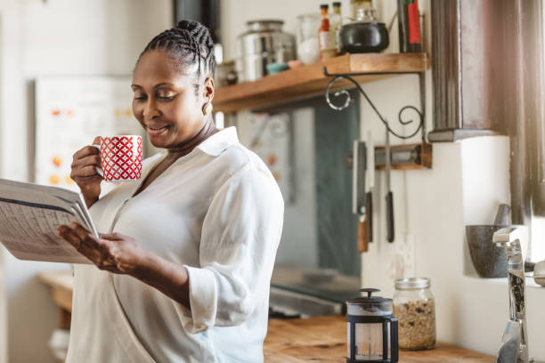 afroamerykanka czyta gazetę przy kawie w domu - reading newspaper break tea zdjęcia i obrazy z banku zdjęć